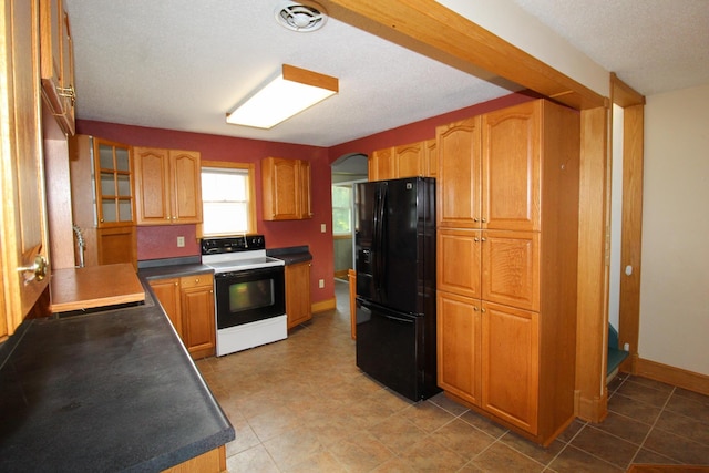 kitchen featuring glass insert cabinets, baseboards, black fridge with ice dispenser, dark countertops, and electric range