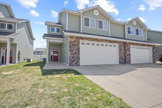 2344 NW 14th St, Minot, ND 58703 - townhome / multi-family property with fence, an attached garage, stone siding, driveway, and a front yard