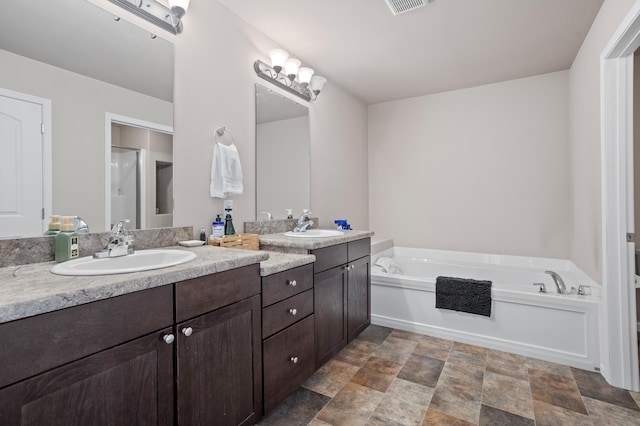 2344 NW 14th St, Minot, ND 58703 - bathroom featuring a sink, double vanity, a garden tub, and stone finish flooring