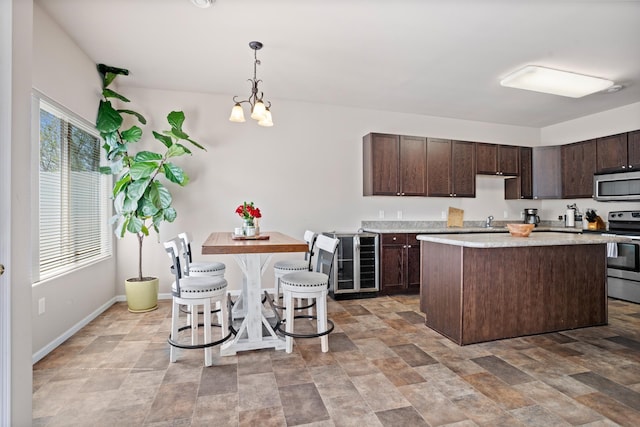 2344 NW 14th St, Minot, ND 58703 - kitchen with a center island, stone finish flooring, dark brown cabinetry, light countertops, and appliances with stainless steel finishes
