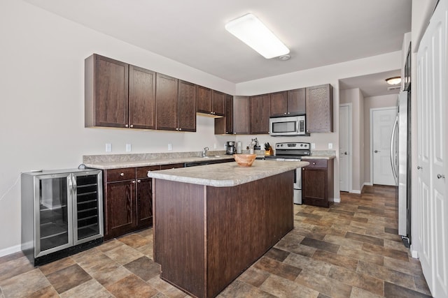 2344 NW 14th St, Minot, ND 58703 - kitchen featuring wine cooler, stainless steel appliances, stone finish floor, dark brown cabinets, and light countertops
