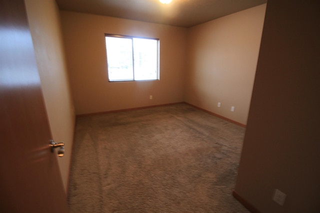 unfurnished room with carpet flooring and baseboards