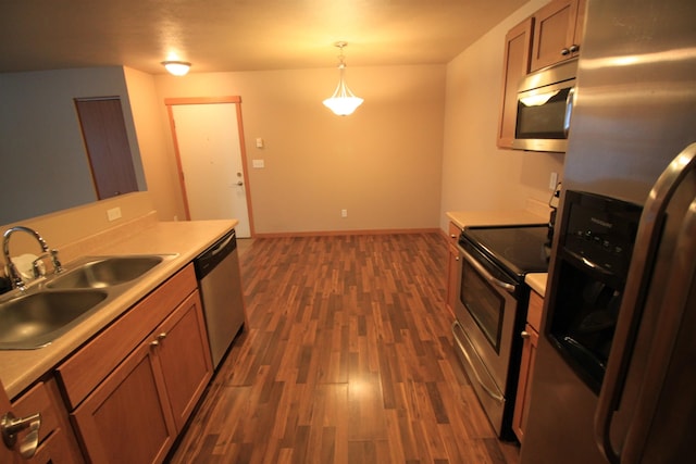 kitchen with stainless steel appliances, a sink, dark wood finished floors, and light countertops