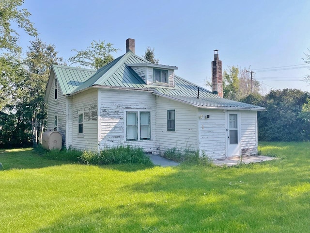222 2nd Ave, Kramer, ND 58748 - rear view of property with a chimney, a lawn, and metal roof