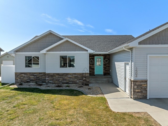 1504 Valley Bluffs Dr, Minot, ND 58701 - view of front of house featuring stone siding, a garage, a front yard, and a shingled roof