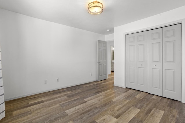 1504 Valley Bluffs Dr, Minot, ND 58701 - unfurnished bedroom featuring wood finished floors, a closet, and baseboards
