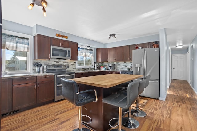 1722 1st St, Minot, ND 58701 - kitchen featuring appliances with stainless steel finishes, a kitchen breakfast bar, butcher block counters, a sink, and light wood-style floors