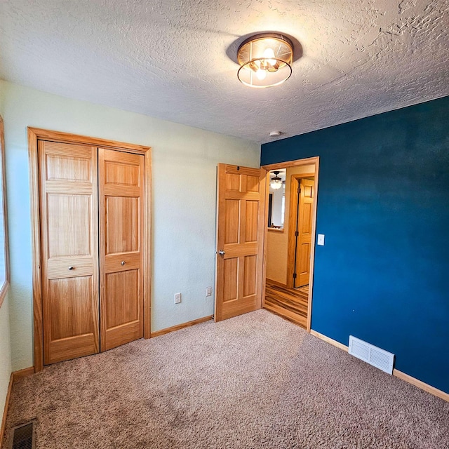 611 16th St, Minot, ND 58701 - unfurnished bedroom with a closet, carpet, a textured ceiling, and baseboards