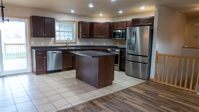 611 16th St, Minot, ND 58701 - kitchen featuring appliances with stainless steel finishes, a sink, dark countertops, a kitchen island, and dark brown cabinetry