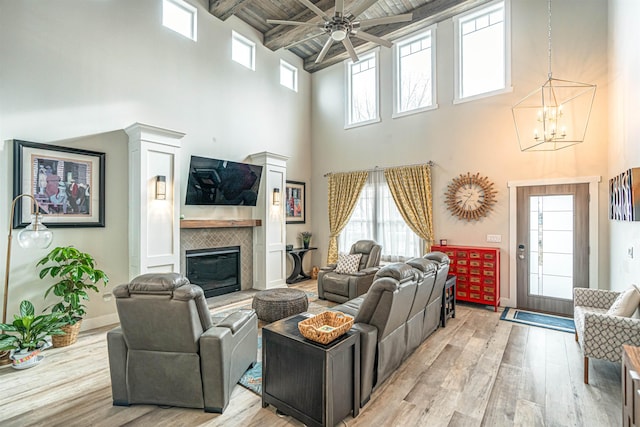 615 2nd St, Garrison, ND 58540 - living area with a high ceiling, light wood-style floors, a tile fireplace, ceiling fan, and beam ceiling
