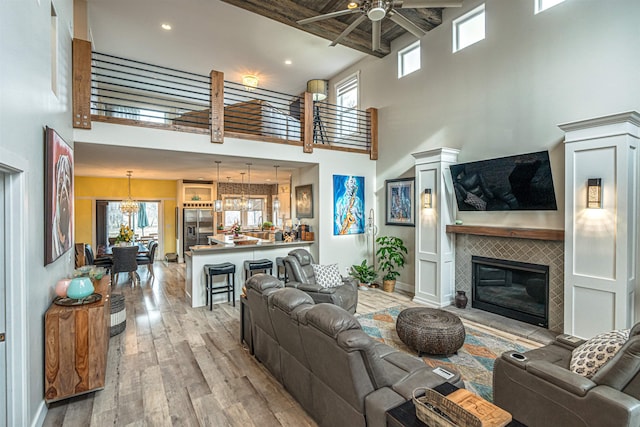 615 2nd St, Garrison, ND 58540 - living area with a ceiling fan, a towering ceiling, wood finished floors, a tile fireplace, and healthy amount of natural light