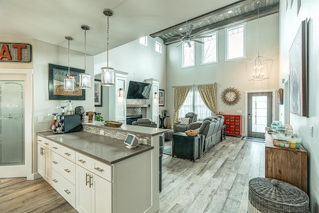 615 2nd St, Garrison, ND 58540 - kitchen featuring a peninsula, a chandelier, white cabinetry, a towering ceiling, and light wood-type flooring