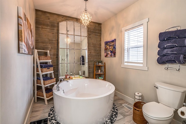 615 2nd St, Garrison, ND 58540 - full bath featuring baseboards, a soaking tub, toilet, wood walls, and a chandelier