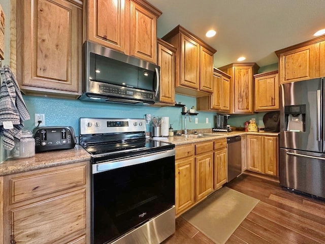 1312 28th St, Minot, ND 58703 - kitchen featuring appliances with stainless steel finishes, a sink, dark wood-style floors, recessed lighting, and light stone counters