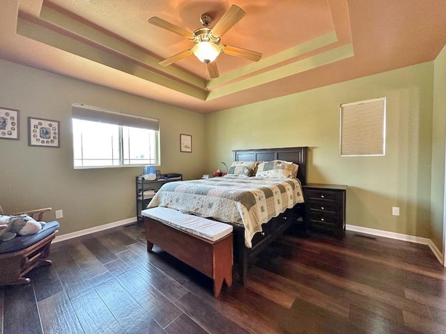1312 28th St, Minot, ND 58703 - bedroom featuring a tray ceiling, dark wood-style flooring, baseboards, and a ceiling fan