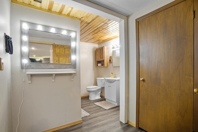 1001 20th St, Minot, ND 58703 - bathroom featuring wood finished floors, toilet, vanity, baseboards, and wood ceiling