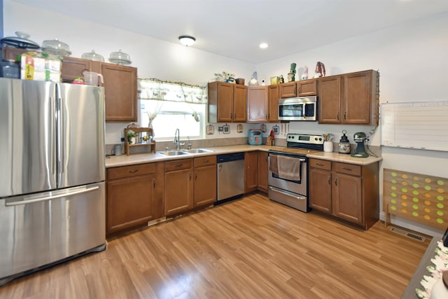 321 6th St, Minot, ND 58703 - kitchen featuring appliances with stainless steel finishes, a sink, light countertops, and light wood-style flooring