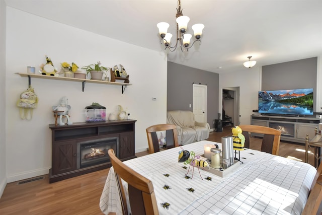 321 6th St, Minot, ND 58703 - dining space featuring a chandelier, a glass covered fireplace, light wood finished floors, and baseboards