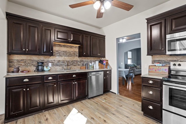 706 E Central Ave, Minot, ND 58701 - kitchen featuring stainless steel appliances, arched walkways, a ceiling fan, a sink, and decorative backsplash