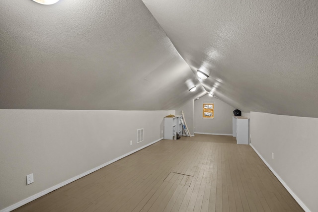 706 E Central Ave, Minot, ND 58701 - bonus room with a textured ceiling, vaulted ceiling, baseboards, and wood-type flooring