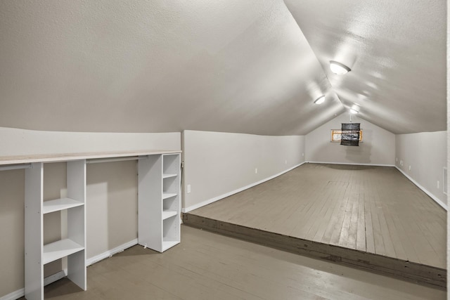 706 E Central Ave, Minot, ND 58701 - additional living space featuring a textured ceiling, vaulted ceiling, baseboards, wood-type flooring, and built in shelves
