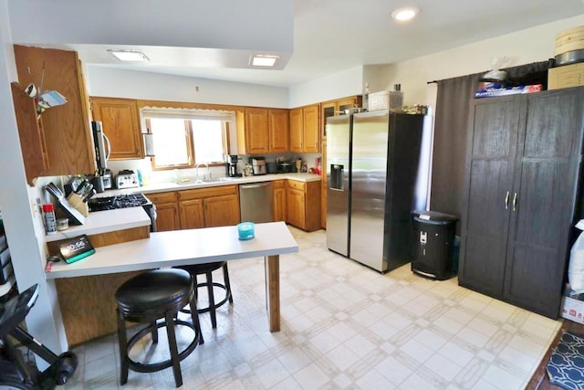306 Davis St, Burlington, ND 58722 - kitchen featuring appliances with stainless steel finishes, light countertops, brown cabinetry, a sink, and light floors