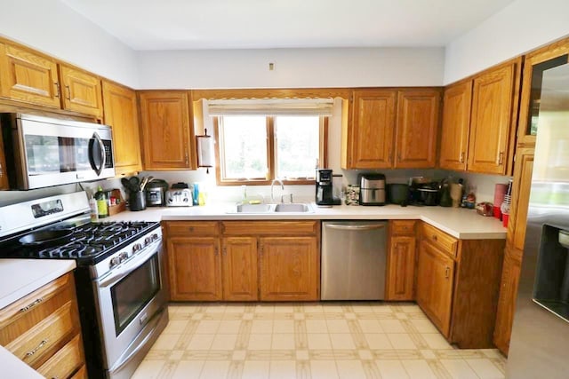 306 Davis St, Burlington, ND 58722 - kitchen featuring appliances with stainless steel finishes, a sink, light floors, and brown cabinets
