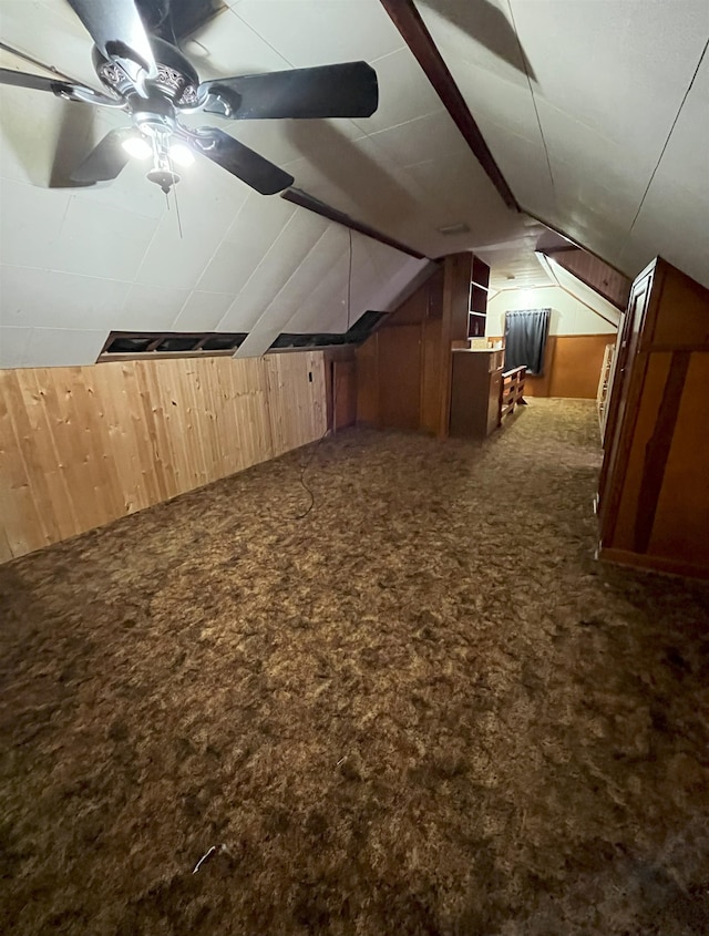 909 NW 10th Ave, Minot, ND 58703 - additional living space with carpet floors, wood walls, lofted ceiling, and ceiling fan