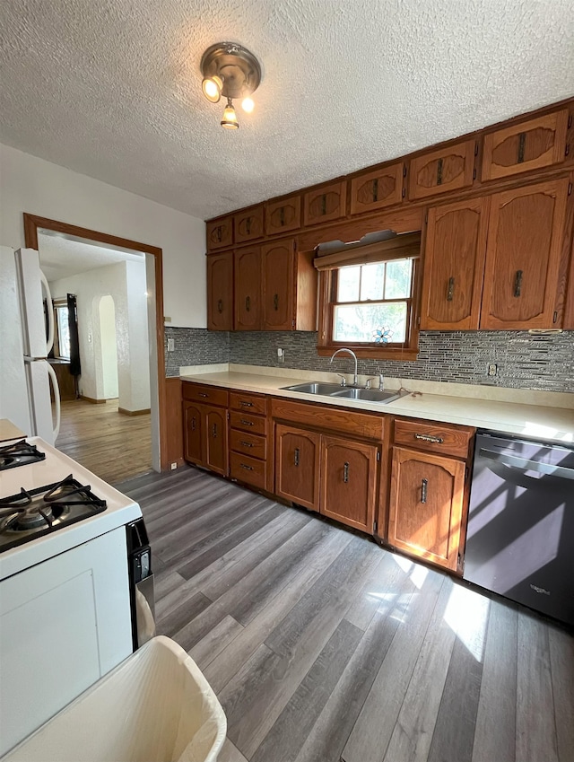 909 NW 10th Ave, Minot, ND 58703 - kitchen with a sink, white appliances, brown cabinetry, light countertops, and a textured ceiling