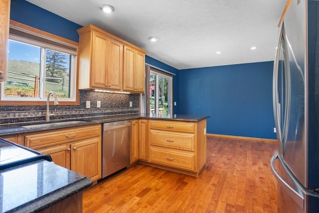 4401 38th St, Minot, ND 58701 - kitchen featuring appliances with stainless steel finishes, a sink, decorative backsplash, a peninsula, and light wood-style flooring