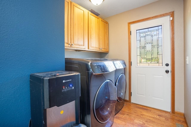4401 38th St, Minot, ND 58701 - washroom with washer and clothes dryer, cabinet space, and light wood-type flooring