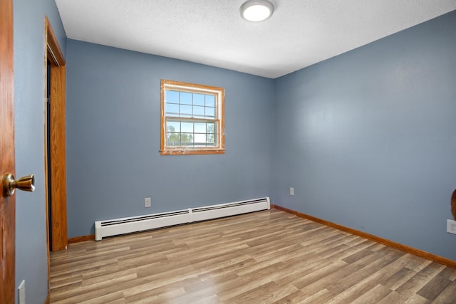 3574 91st St, Mohall, ND 58761 - empty room with baseboard heating, wood finished floors, a textured ceiling, and baseboards