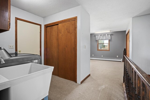 3574 91st St, Mohall, ND 58761 - laundry area with a baseboard heating unit, carpet, washing machine and dryer, a textured ceiling, and baseboards
