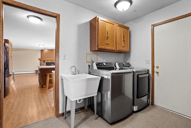 3574 91st St, Mohall, ND 58761 - laundry room featuring cabinet space, washer and clothes dryer, a baseboard heating unit, and a textured ceiling