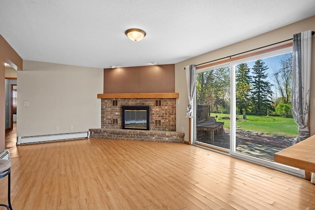 3574 91st St, Mohall, ND 58761 - unfurnished living room with a baseboard heating unit, wood finished floors, a fireplace, and a textured ceiling