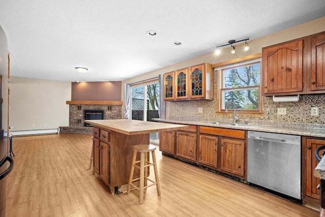 3574 91st St, Mohall, ND 58761 - kitchen featuring dishwasher, a sink, light wood finished floors, a fireplace, and decorative backsplash