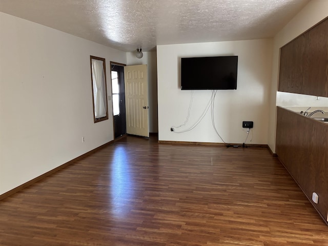 2420 8th St Unit 2420, Minot, ND 58703 - unfurnished living room featuring dark wood finished floors, a textured ceiling, and baseboards