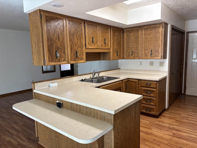 2420 8th St Unit 2420, Minot, ND 58703 - kitchen featuring a sink, wood finished floors, brown cabinets, light countertops, and a textured ceiling