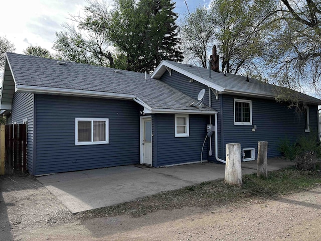 410 6th Ave, Minot, ND 58703 - back of house featuring a chimney, a patio, roof with shingles, and fence