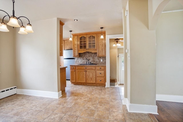 1309 1st St, Minot, ND 58701 - kitchen featuring freestanding refrigerator, a sink, tasteful backsplash, arched walkways, and baseboards