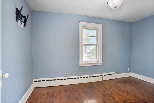 1309 1st St, Minot, ND 58701 - spare room with baseboard heating, baseboards, and hardwood / wood-style flooring