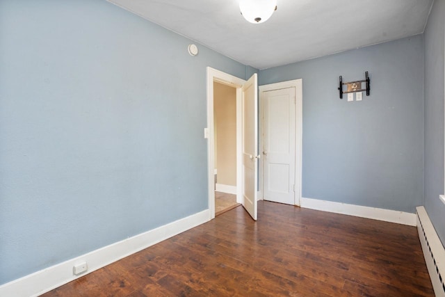 1309 1st St, Minot, ND 58701 - empty room featuring a baseboard heating unit, baseboards, wood finished floors, and a smoke detector