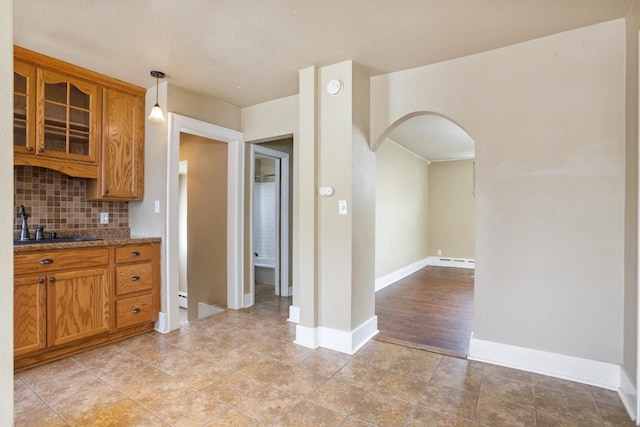 1309 1st St, Minot, ND 58701 - kitchen with arched walkways, tasteful backsplash, glass insert cabinets, stone counters, and baseboards