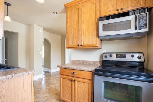 1309 1st St, Minot, ND 58701 - kitchen featuring white microwave, electric stove, arched walkways, light countertops, and baseboards
