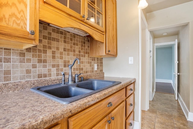 1309 1st St, Minot, ND 58701 - kitchen with a sink, tasteful backsplash, glass insert cabinets, tile patterned flooring, and light countertops