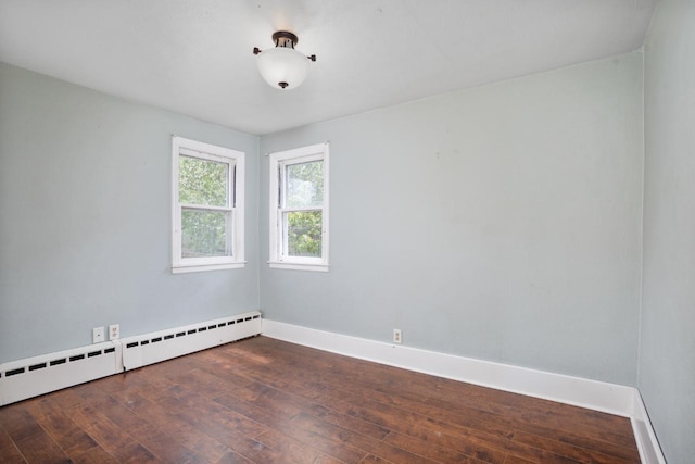 1309 1st St, Minot, ND 58701 - spare room featuring baseboard heating, hardwood / wood-style flooring, and baseboards