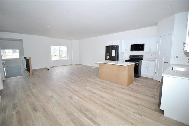 138 Mulberry Loop, Minot, ND 58703 - kitchen featuring range with electric stovetop, black fridge, a kitchen island, light wood-style flooring, and open floor plan
