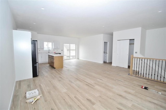 138 Mulberry Loop, Minot, ND 58703 - unfurnished living room with light wood-style floors, a sink, and baseboards