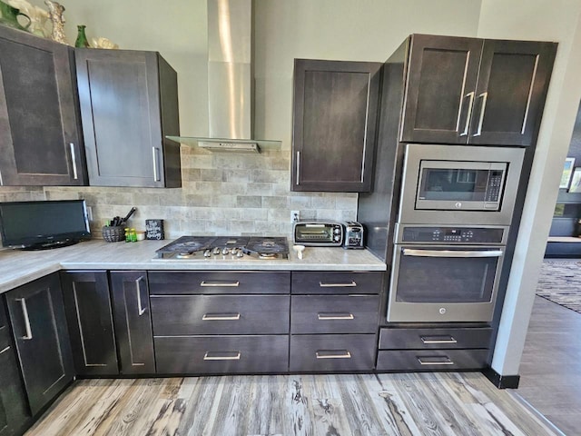 1007 5th St, Rugby, ND 58368 - kitchen with stainless steel appliances, wall chimney exhaust hood, light wood finished floors, decorative backsplash, and light countertops