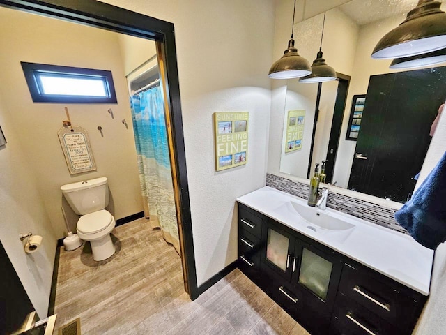 1007 5th St, Rugby, ND 58368 - bathroom with toilet, vanity, baseboards, and wood finished floors